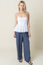 Woman wearing a white top and blue pants against a plain background