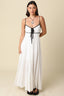 Front view of the Santorini Contrast Tie Maxi Dress in white, featuring a sweetheart neckline with black contrast trim, front tie detail with black ribbon, and tiered flowing maxi skirt