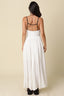 Side view of the Santorini Contrast Tie Maxi Dress in white with black contrast trim, showing the flowing full-length silhouette, adjustable spaghetti straps, and softly structured bodice with front tie detail