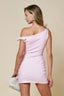 Woman wearing a pink one-shoulder dress against a beige background