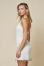 Woman wearing a white dress with lace details on a beige background