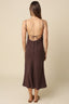 Woman wearing a brown slip dress with open back on a beige background