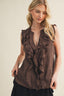 Woman wearing a brown ruffled top against a beige background