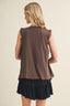 Woman wearing a brown top and black skirt on a beige background