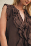 Brown ruffled top worn by a person on a neutral background
