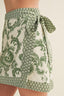 Green and white patterned wrap skirt on a neutral background