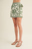Green and white patterned skirt worn by a person on a beige background