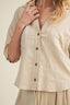 Beige blouse with button details on a plain background