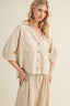Woman wearing a beige linen outfit on a plain background