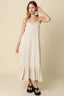 Woman wearing a beige slip dress against a plain background