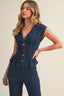 Woman wearing a denim peplum top and pants on a beige background