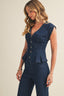 Woman wearing a navy blue sleeveless top with buttons and matching pants on a beige background