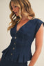 Woman wearing a blue denim top with buttons on a plain background