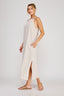 Woman wearing a white ribbed dress on a plain background