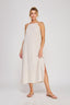 Woman wearing a white dress with a slit on a plain background