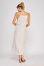 Woman wearing a white dress with thin straps on a plain background
