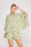Woman wearing a light green outfit with floral patterns on a white background