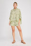 Woman wearing a light green shirt and shorts set on a white background