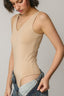 Woman wearing a beige bodysuit with a plain background