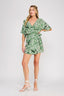 Woman wearing a green leaf-patterned dress on a white background
