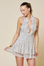 Woman wearing a light-colored halter dress with ruffled details on a beige background