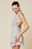 Woman wearing a light-colored, layered dress against a beige background