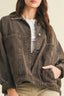 Person wearing a dark denim jacket over a white shirt with a neutral background