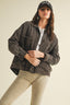 Woman wearing a dark denim jacket and cap on a plain background