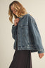 Woman wearing a blue denim jacket against a beige background