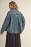 Person wearing a blue denim jacket on a plain background