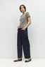 A woman modeling a taupe short-sleeve top and dark navy wide-leg trousers with black flats, standing against a plain white studio background.