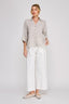 Woman wearing a striped shirt and white pants on a plain background
