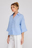 Woman wearing a blue checkered shirt with white pants on a plain background