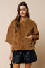 Woman wearing a brown faux fur jacket with a beige background