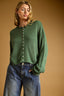 Woman wearing a green sweater with a brown background