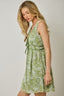 Woman wearing a green floral dress against a plain background