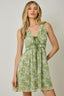Woman wearing a green floral dress against a neutral background