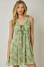 Woman wearing a green floral dress against a plain background
