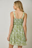 Woman wearing a green floral dress against a plain background