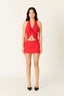 Woman wearing a red dress with a halter neck and cut-out design on a white background
