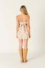 Woman wearing a strapless dress with a bow detail and tan boots on a white background