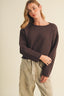 Front view of the Driftwood Bateau Neck Crop Sweater in deep espresso brown, featuring a wide bateau neckline, boxy cropped silhouette, long sleeves with rolled-edge cuffs, and a substantial garter stitch knit texture