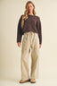 Three-quarter side view of the Driftwood Bateau Neck Crop Sweater in deep brown, showing the slightly cropped torso length, relaxed boxy fit, and long sleeves with rolled-edge cuff detail