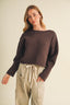 Close-up detail shot of the Driftwood Bateau Neck Crop Sweater shoulder and neckline area, highlighting the wide bateau neckline construction, dropped shoulder seam, and the matte horizontal garter stitch knit texture in deep espresso brown