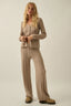 Woman wearing a beige knitted outfit on a plain background