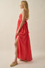 Woman wearing a red dress with a slit on a beige background
