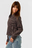 Woman wearing a brown western stitch design jacket and blue jeans against a white background