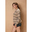 Woman wearing a striped sweater and denim shorts against a beige background
