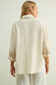 Woman wearing a beige shirt against a plain background