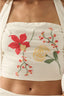 White top with floral embroidery on a person wearing it.